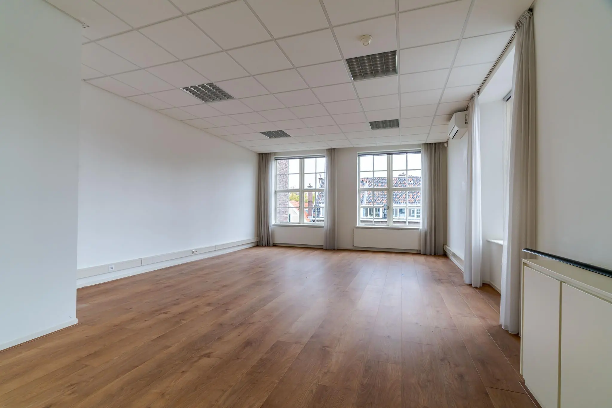 Licht en ruim leegstaand kantoor aan het Lange Voorhout met houten vloer en grote ramen.